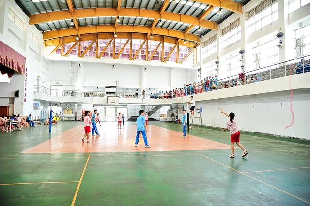 Pupils playing a volleyball match in a school gymnasium.